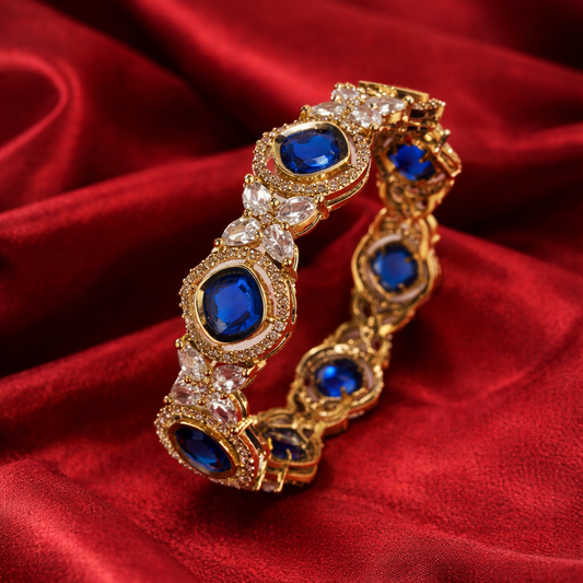 Gold bracelet with blue stones on a red fabric background