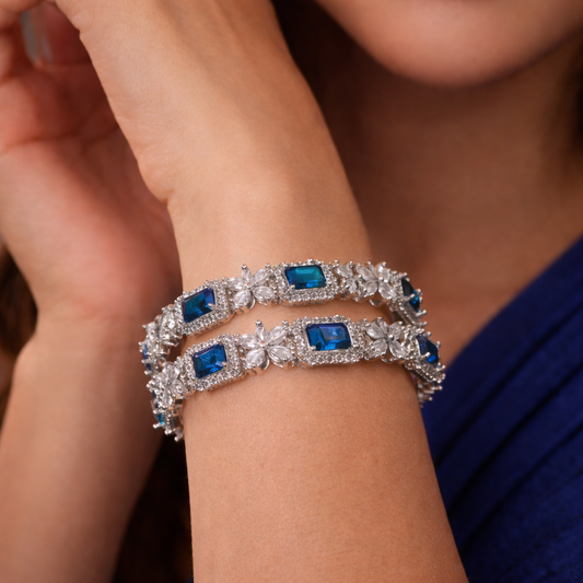 Silver bracelet with blue gemstones on a person's wrist against a blurred background