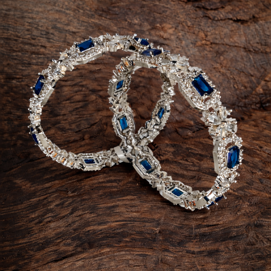 Pair of silver bracelets with blue stones on a wooden surface