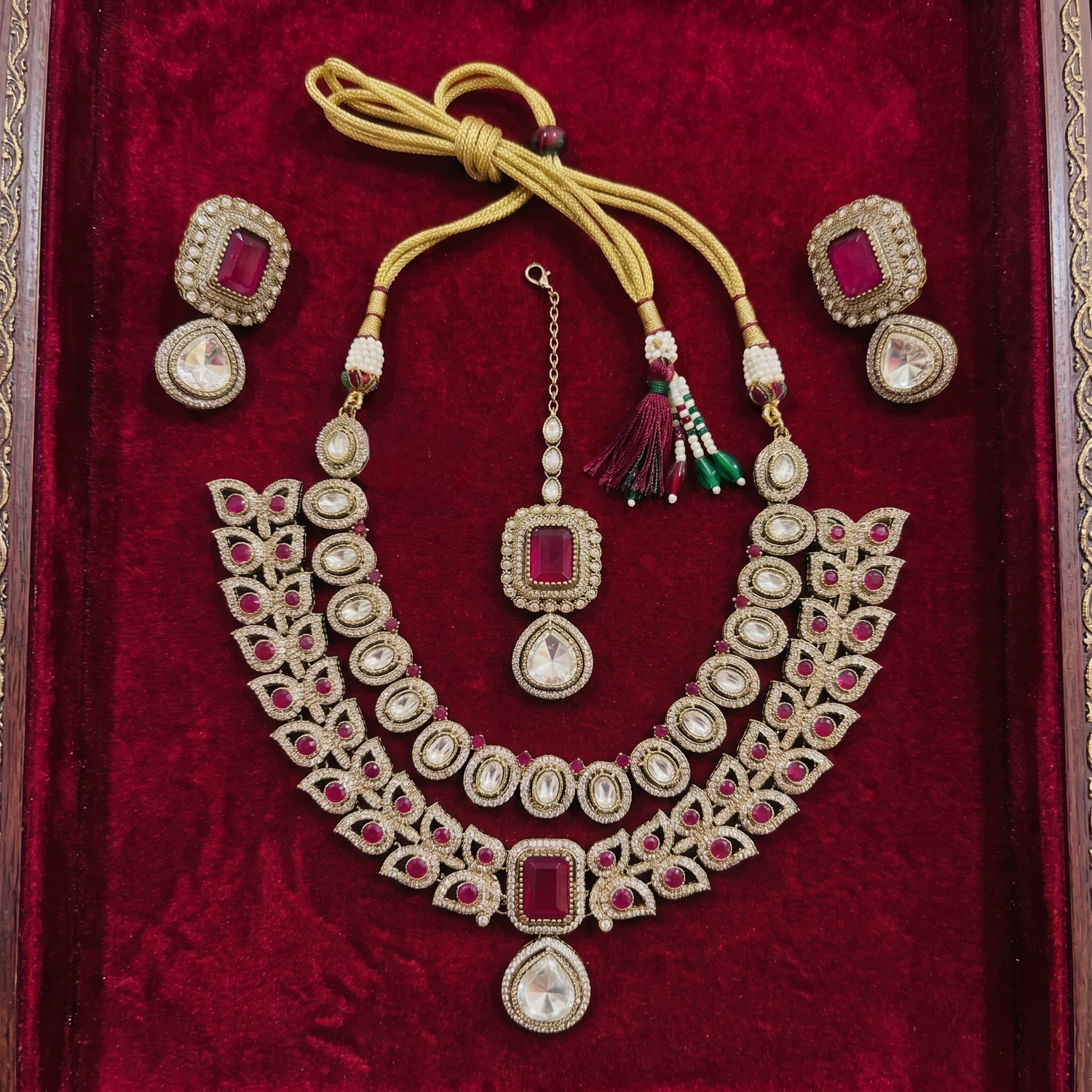 gold-plated layered jewellery set by Auraa Trends featuring red and white kundan stones